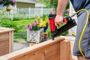 Man using a pneumatic nail gun to construct cedar garden planters