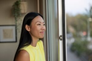 essential pest management tips for a pest-free home, happy asian woman looking through the window of her home